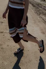 Sandalias negras de cuero con tira ancha sobre el empeine adornada con apliques circulares plateados.