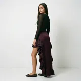 Falda asimétrica de corte high-low, con diseño de volados en cascada a lo largo del borde delantero y ruedo con volado inferior. Confeccionada en tela satinada de color bordó.
