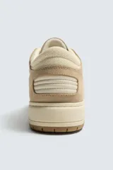 Zapatillas deportivas de caña baja color beige, con cordones y suela gruesa.