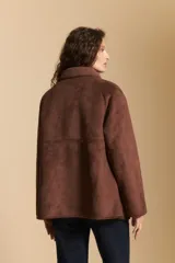 Gamulán de gamuza sintética color marrón con interior de corderito al tono. Presenta cuello amplio, cierre frontal con botones y diseño de silueta relajada.