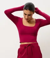 Blusa cropped deportiva femenina Get Over, confeccionada en microfibra de poliamida y elastano, de color fucsia, con escote cuadrado, manga larga y puños con abertura para pulgar.