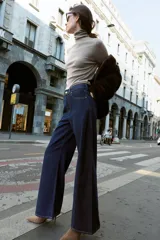 Jeans de tiro alto con pernera ancha y diseño combinado en dos tonos de denim. El panel central es de un lavado azul medio, mientras que los paneles laterales son de un lavado azul oscuro. Presenta cinco bolsillos y cierre frontal con cremallera y botón.