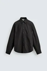 Sobrecamisa de corte relajado confeccionada en denim de algodón con diseño a rayas verticales. Presenta cuello solapa, cierre frontal de botones, manga larga con puños abotonados y un bolsillo plastrón en el pecho.