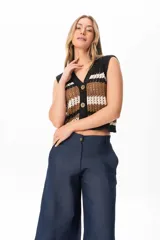 Chaleco tejido a crochet con rayas horizontales en negro, marrón y blanco. Tiene cuello en V y cierre frontal con botones de madera.