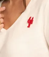 Remera de mangas cortas color crema, confeccionada en tejido flamé, con escote en pico y bordado delantero de langostas rojas.