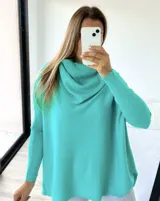 Polerón de punto color verde agua, con diseño mega oversize y cuello caído tipo polera. Presenta mangas largas con puños acanalados.