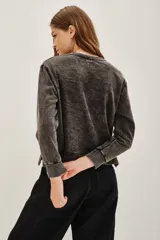 Buzo de cuello redondo con efecto lavado stonewash, manga larga y puños acanalados. Presenta una estampa frontal de estilo rockero con motivos gráficos y detalles en color rojo.