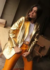 Blazer de cuero dorado metalizado, con bolsillos frontales aplicados, solapas clásicas y cierre con grandes botones de nácar.