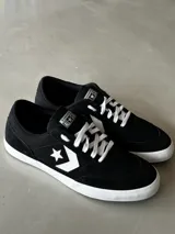 Championes urbanos Converse Net Star, de caña baja, color negro con detalles en blanco. Capellada de lona de algodón combinada con gamuza, logo Star Chevron aplicado, cordones de poliéster blancos y suela de caucho.