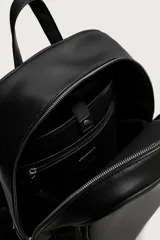 Mochila de acabado liso en color negro, con compartimento principal con cierre de cremallera, bolsillo frontal, detalle de hebillas en los laterales y asas acolchadas.