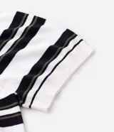 Remera boxy de punto listrado en blanco, negro y verde oliva, con cuello polo y abertura frontal con botones. Posee caída cómoda y textura suave.