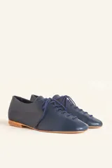 Zapato tipo oxford plano de cuero vacuno en color azul marino, con cordones al tono y suela de cuero.