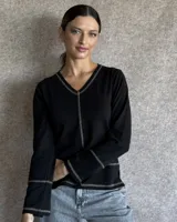 Remera de manga larga color negro con cuello en V. Presenta costuras decorativas a la vista en tono contrastante en el cuello, el centro, los puños y el ruedo.