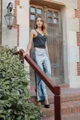 Top negro con breteles finos y escote en V. Presenta un nudo con aro metálico en la parte inferior del busto y un corte en el abdomen.