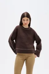 Sweater de punto color marrón, de corte holgado y cuello redondo. Presenta detalles de costuras decorativas en contraste a lo largo de las mangas, el cuello y el ruedo.