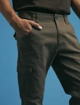 Pantalon cargo de corte recto en color verde militar, confeccionado en sarga de algodón con elastano. Presenta bolsillos laterales con fuelle y tapa, además de bolsillos traseros con cierre de botón.