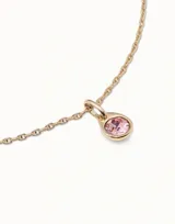 Charm de metal bañado en oro con cristal rosa facetado en forma circular.