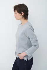 Remera de manga larga con cuello redondo, confeccionada en tejido de punto gris melange con costuras visibles en contraste.