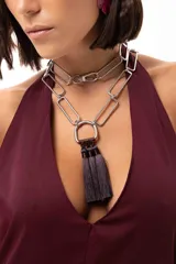 Collar versátil con cadena de eslabones rectangulares metálicos, diseñado para usarse largo o corto de forma doble. Presenta un dije central en forma de herradura del que cuelgan tres borlas de hilo en tono oscuro.