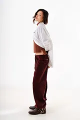 Pantalón de denim con efecto lavado, de corte recto y tiro bajo. Cuenta con cordones ajustables en los tobillos para modificar la silueta y cierre frontal con botón y cremallera.
