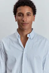 Camisa de manga larga con cuello clásico y cierre frontal de botones. Presenta un diseño de rayas verticales finas en tonos claros.