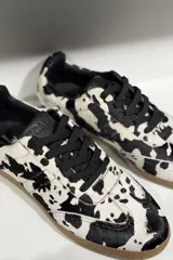 Championes de cuero vacuno con acabado brillante tipo charol, color azul marino, con cordones al tono y suela de goma color caramelo.