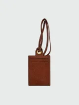 Tarjetero de cuero color marrón con textura granulada, diseñado para colgar. Cuenta con una ranura para tarjetas, costuras reforzadas en color claro y un ojal metálico dorado para la correa ajustable.