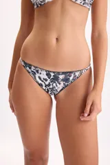 Bombacha de bikini con estampa animal print en tonos negro, blanco y marrón, con costuras decorativas tipo crochet en color negro en los bordes.