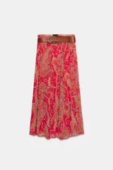 Falda larga de corte fluido con estampado paisley en tonos rojos, naranjas y celestes. Cuenta con cintura elástica y viene con un cinturón de cuero marrón con hebilla metálica dorada.