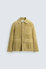 Cazadora de hombre de corte relajado, confeccionada en piel con acabado ante color mostaza/verde oliva. Presenta cuello solapa, manga larga con puño abotonado, cierre frontal de botonadura y cuatro bolsillos de plastrón visibles (uno en el pecho y tres en la parte inferior).