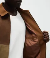 Chaqueta Marfinno de corte recto con diseño de bloques en tonos tierra, confeccionada en poliuretano con base de poliéster. Presenta cuello camisero estructurado, cierre frontal con zíper, mangas largas y forro interior con bolsillo funcional.