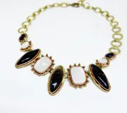 Collar de bronce con piedras naturales engarzadas. Presenta piedras rectangulares blancas nacaradas y piedras ovaladas negras, todas con bordes dorados texturizados.
