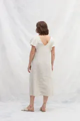 Vestido midi de lino en color azul, con escote en V tanto en el frente como en la espalda. Presenta mangas cortas con vuelo, silueta amplia y cintas verticales a contratono en el frente que estilizan la figura. Incluye bolsillos laterales.