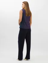 Conjunto de tres piezas compuesto por una musculosa recta, un cardigan liviano de frente abierto con mangas 3/4 y un pantalón de seda fría. La musculosa y el cardigan están confeccionados en tejido plisado con hilos metalizados tornasolados. Incluye collar removible y forro interno a tono.