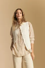 Camisa blanca de manga larga con textura calada o bordada, cuello camisero y corte holgado.