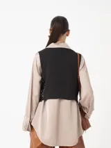 Chaleco con frente cubierto de lentejuelas doradas y espalda de tela viscosa lisa en color negro. Presenta un diseño sin mangas con cierre frontal de un botón.