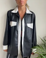 Camisa negra con estampado de piel de cocodrilo, detalles en blanco en cuello, solapa, bolsillos y puños.