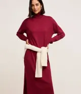 Vestido de punto color rojo oscuro (bordó/vino), de manga larga y corte recto hasta el tobillo. Presenta cuello alto tipo tortuga.