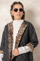 Campera acolchada de corte amplio y largo midi, color beige con diseño capitoneado. Presenta mangas tres cuartos con puños vueltos que revelan un interior estampado con motivo animal print. Diseño sin cuello y cierre frontal oculto.