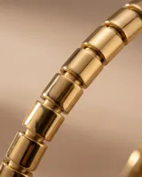 Pulsera esclava rígida de acero con baño de oro, compuesta por eslabones cilíndricos unidos entre sí.