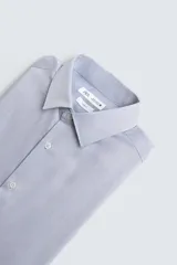 Camisa de algodón de manga larga, color celeste claro, con cuello italiano y cierre frontal de botonadura.