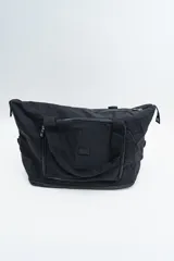 Bolso de viaje tipo duffle, color negro, con cierre principal superior, bolsillo frontal con cierre y doble asa de mano.