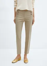 Pantalon de corte skinny en color beige, confeccionado en mezcla de algodón. Presenta un diseño crop con botones decorativos en la parte frontal, cierre oculto de cremallera y gancho, bolsillos laterales y bolsillos de ribete en la parte posterior.