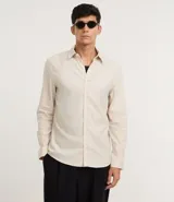 Camisa de manga larga confeccionada en tricolina de algodón, con cuello inglés, cierre frontal abotonado y puños con botones.