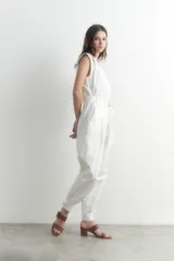 Mono largo blanco con cierre frontal, cinturón con hebilla metálica y detalles de tul en los hombros.