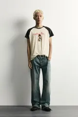 Camiseta regular fit de corte clásico con efecto lavado, cuello redondo negro y mangas cortas ranglán negras. El cuerpo es de color blanco con estampa frontal inspirada en automovilismo con el texto "Asphalt Speed".