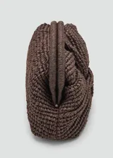 Bolso tipo clutch color marrón de tejido de fibra natural con diseño trenzado y nudo frontal. Cuenta con cierre de marco a presión y forro interior.