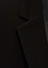 Chaqueta de corte sastre en color negro, con cuello de solapa con muesca, cierre frontal de un botón, bolsillos con solapa y mangas largas con puños abotonados.