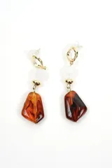 Aros colgantes compuestos por un gancho superior dorado, una cuenta transparente facetada y un dije inferior de resina con efecto carey en tonos marrones.