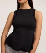 Blusa sin mangas de color blanco confeccionada en tejido punto roma. Presenta un diseño peplum alargado con breteles anchos y volados en el ruedo. Marca Blue Steel.